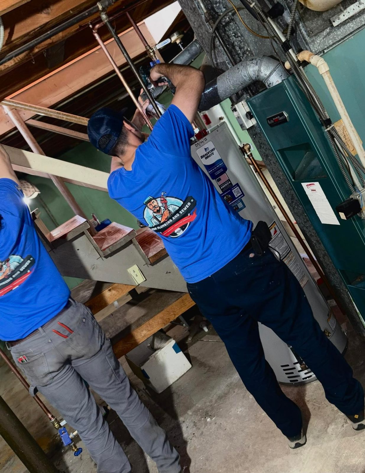 MDM Plumbing technicians in blue branded shirts working on copper piping in a Chicagoland home